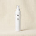 Comfort Zone Essential Milk Cleansing Milk in a white cylindrical pump bottle, set against a textured beige linen background.