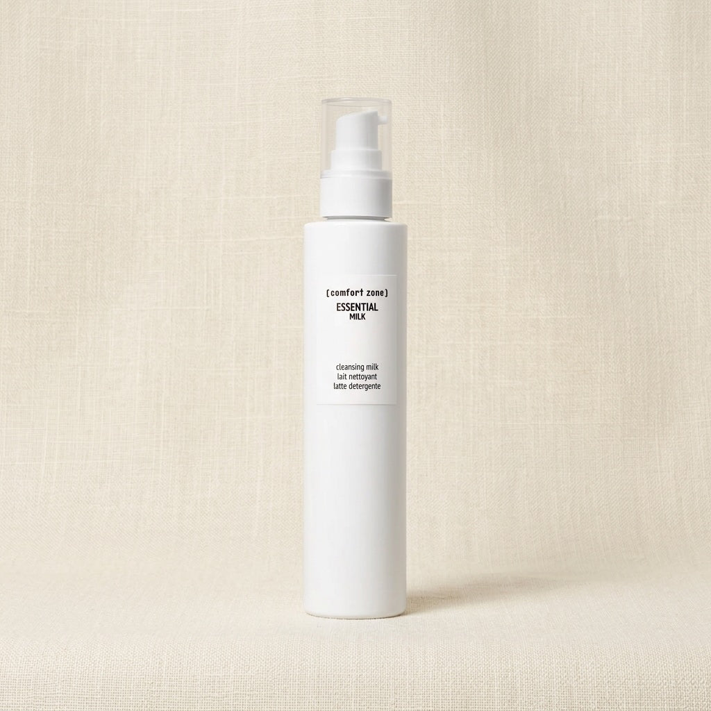 Comfort Zone Essential Milk Cleansing Milk in a white cylindrical pump bottle, set against a textured beige linen background.