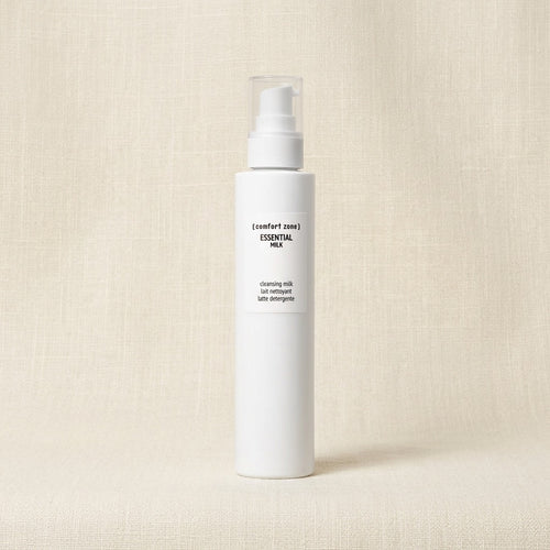 Comfort Zone Essential Milk Cleansing Milk in a white cylindrical pump bottle, set against a textured beige linen background.