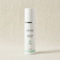 A white cylindrical bottle of Sanitas Sensitive Skin Moisturizer with a silver band and a light green accent stripe, set against a textured beige background.